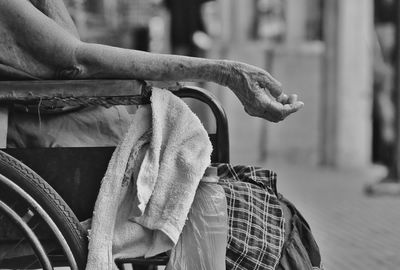 Midsection of female beggar on wheelchair at street