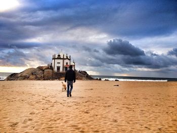 People on beach against cloudy sky