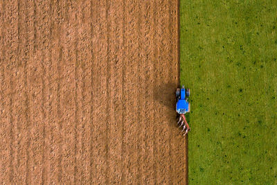Aerial high angle view of tractor ploughing field vertical line