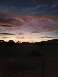 Scenic view of silhouette field against sky at sunset