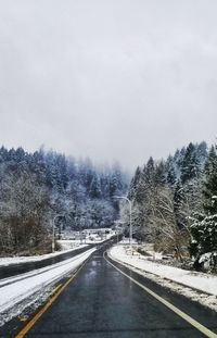 Snow covered road by mountain against sky