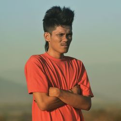 Young man looking away against sky