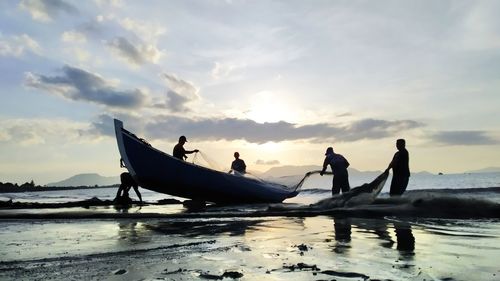 People on beach against sky during sunset