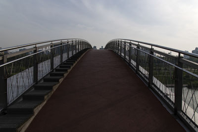 Footbridge over footpath against sky