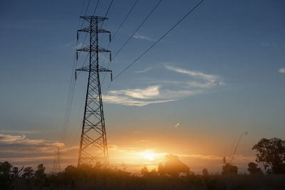 Low angle view of electricity pylon against sky during sunset