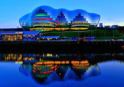 Reflection of illuminated ferris wheel in lake against sky