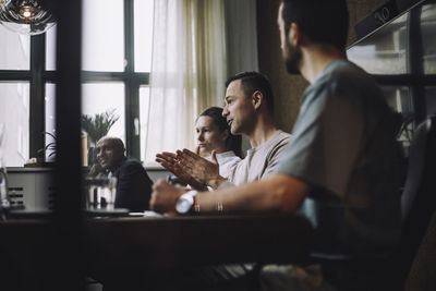 Mature businessman gesturing while sharing ideas with colleagues in meeting room