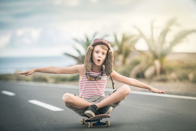 Young woman looking away while sitting on road