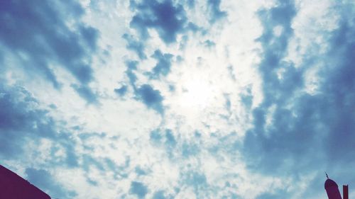 Low angle view of sunlight streaming through clouds