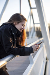 Woman looking at camera while standing on railing