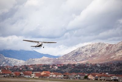 Airplane flying over mountains against sky