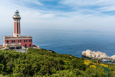 View of lighthouse in sea against cloudy sky