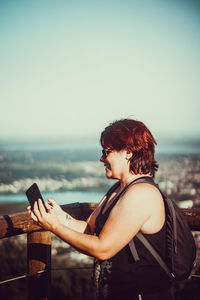 Young woman using mobile phone at beach against sky