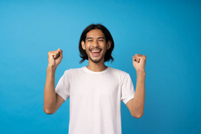 Portrait of smiling man standing against blue background