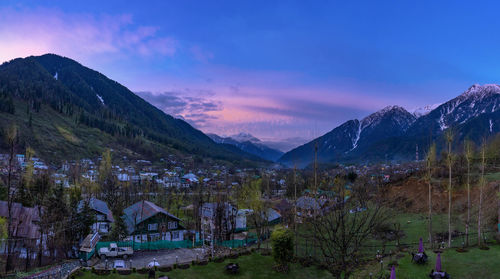 Panoramic view of buildings and mountains against sky at sunset