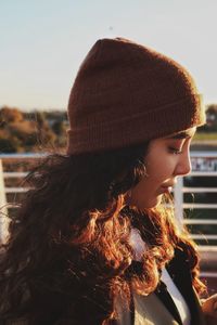 Portrait of young woman looking away against sky