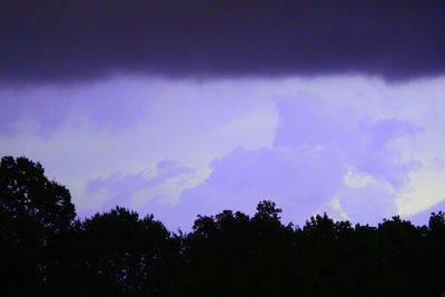 Low angle view of silhouette trees against cloudy sky