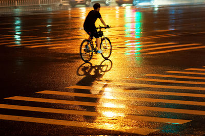 Man riding bicycle on highway at night