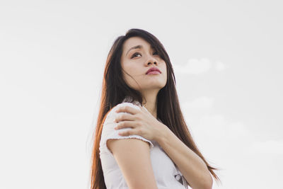 Thoughtful young woman standing against white background