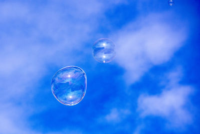 Low angle view of bubbles against blue sky