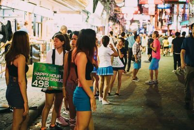Rear view of people walking on street in city