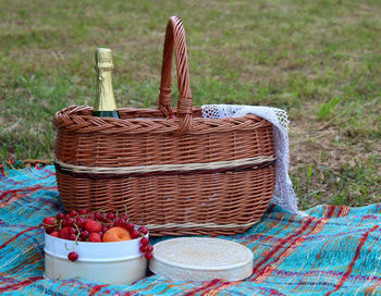 Picnic basket with a bottle of wine and apricot and berries in a round white tin