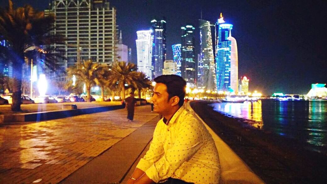 WOMAN LOOKING AT ILLUMINATED CITY SKYLINE