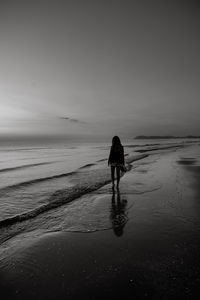 Rear view of man standing on beach against sky