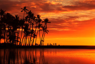 Silhouette palm trees by sea against romantic sky at sunset