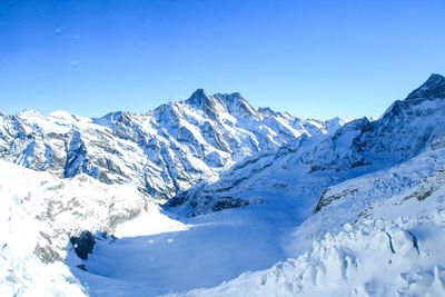 Scenic view of snowcapped mountains against clear blue sky