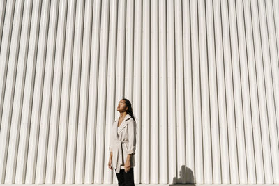 Young elegant woman with eyes closed in front of white wall