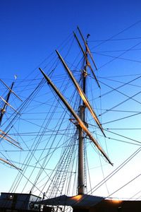 Low angle view of electricity pylon against clear blue sky