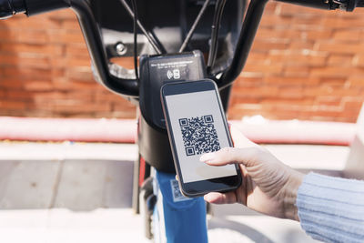 Woman renting electric bicycle through smart phone app