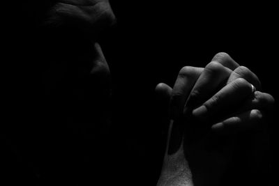 Close-up of man praying against black background