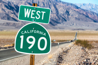 Close-up of signboard on road against mountain range