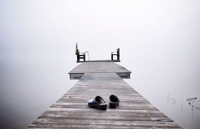 Footwear on wooden pier over calm lake