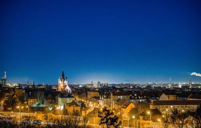 High angle shot of illuminated buildings against blue sky