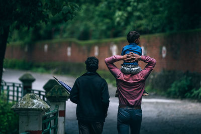 Rear view of men standing against trees