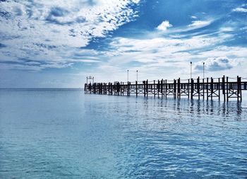 Pier on sea against cloudy sky