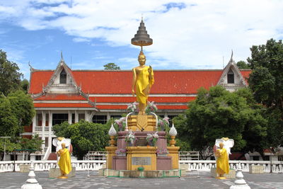 Statue amidst trees and buildings against sky