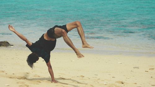 Man doing handstand at sandy beach