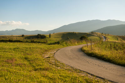 Road leading towards mountains against sky