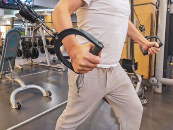 Midsection of man exercising while standing in gym