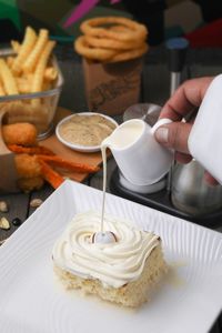 Cropped hand pouring milk on dessert in plate