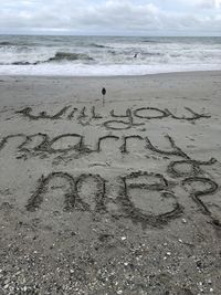 Text on sand at beach against sky