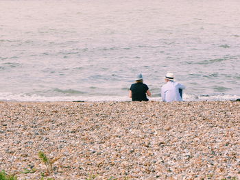 Rear view of couple sitting at beach