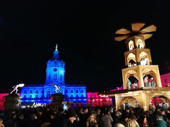 People at illuminated cathedral against sky at night