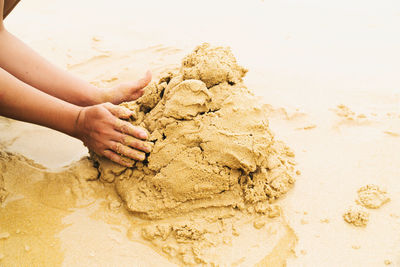 Cropped hand of person standing on sand at beach