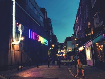 People walking on illuminated street at night