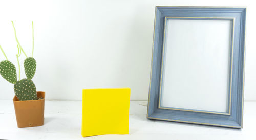 Close-up of picture frame and adhesive note by potted plant on table
